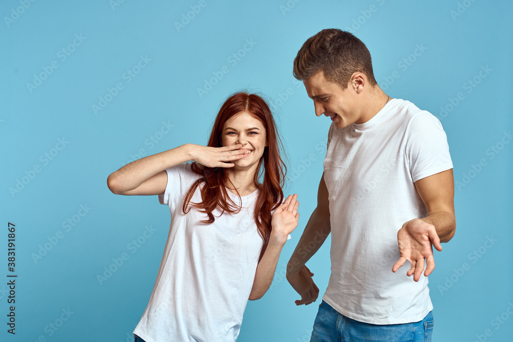 Fototapeta premium enamored man and woman in jeans and a T-shirt on a blue background hug each other and have fun