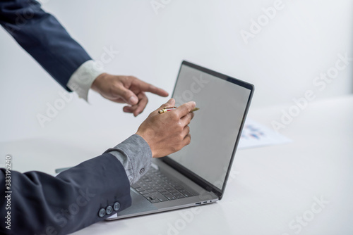Businessman pointing at the information on a laptop with a white screen during a meeting.