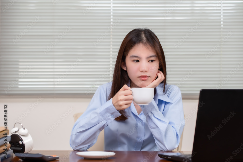 Beautiful asian woman drinking coffee in the morning before work and working on laptop computer. Beautiful asian woman drinking coffee in the morning before work and working on laptop computer.