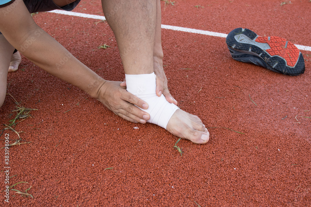 man applying compression bandage onto ankle injury After exercise