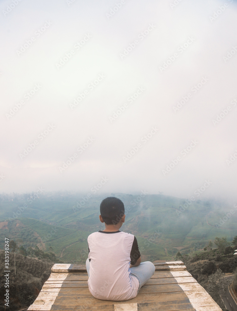 A boy enjoy the view and fog in the morning at top hill