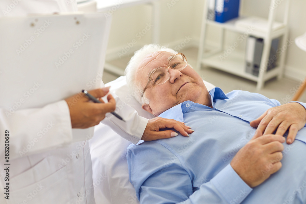Relaxed senior male patient lying on bed in hospital office during medical check-up Relaxed senior male patient lying on bed in hospital office during medical check-up