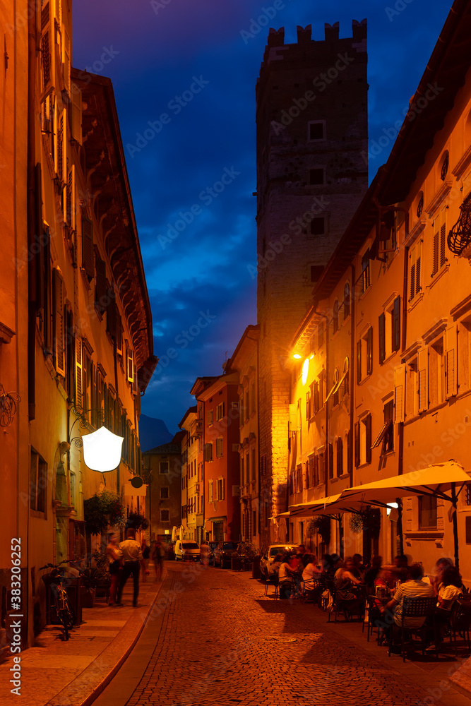 Busy typical street of ancient Italian city of Trento in autumn evening..