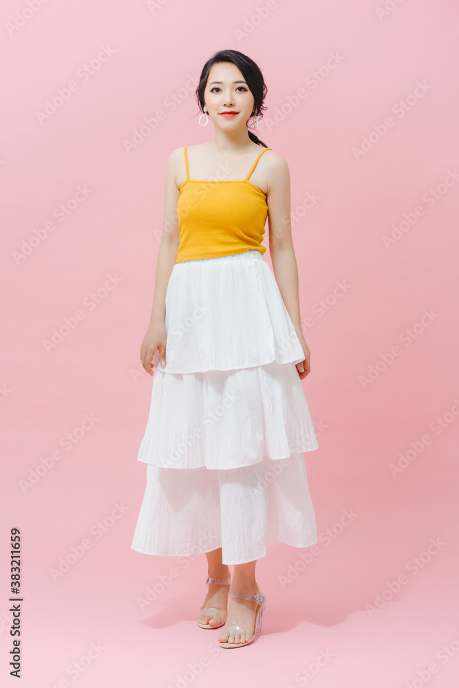 Full length fashion girl in yellow top and white long skirt posing on pink background Full length fashion girl in yellow top and white long skirt posing on pink background