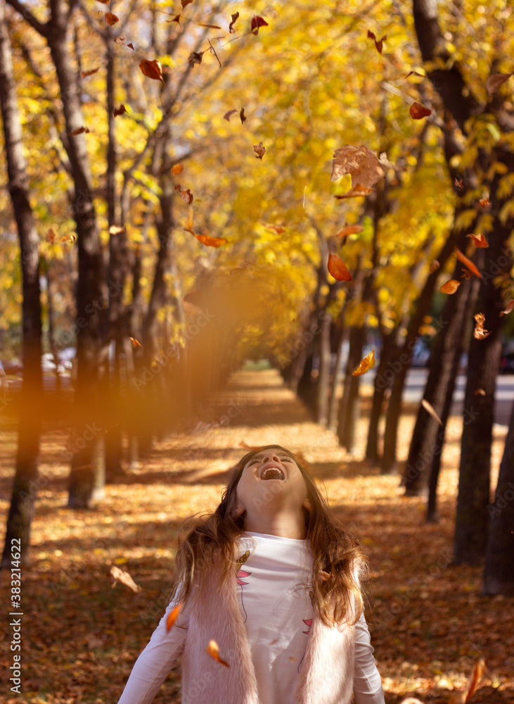 Beautiful little girl throwing fallen leaves, playing in the park; autumn/nature background Beautiful little girl throwing fallen leaves, playing in the park; autumn/nature background