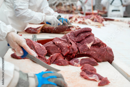 Butcher cuts freshly slaughtered meat of pork for sale and further processing as sausage
