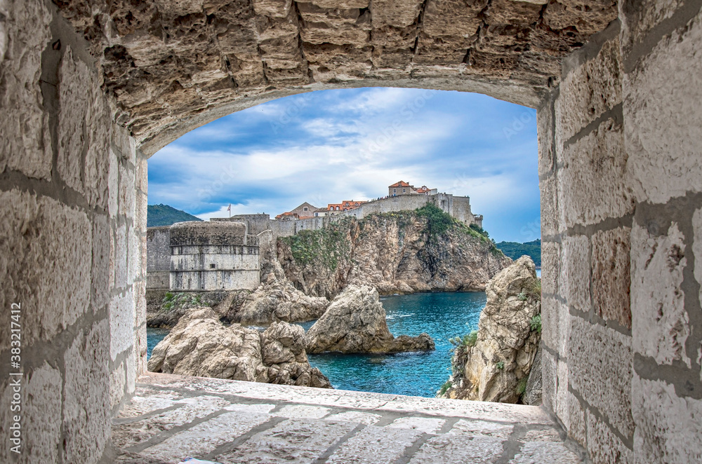 View from stone window of cliffs, sea and Dubrovnik historic wall