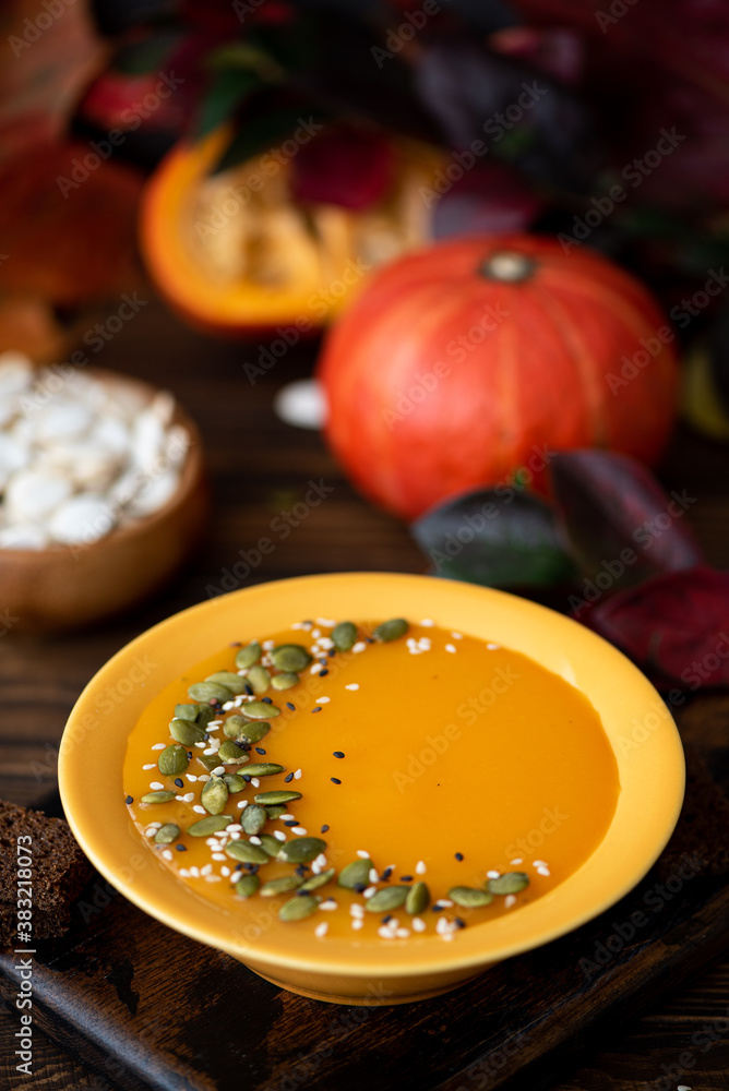 pumpkin cream soup with seeds and sesame seeds in a yellow plate pumpkin cream soup with seeds and sesame seeds in a yellow plate