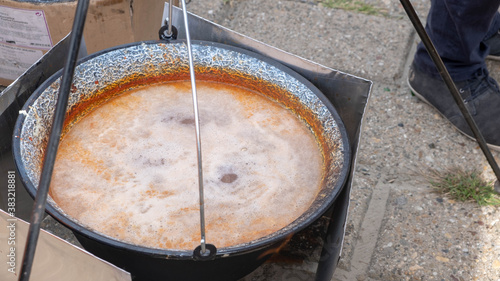 Cooking traditional fish soup on open flame in cooking kettle