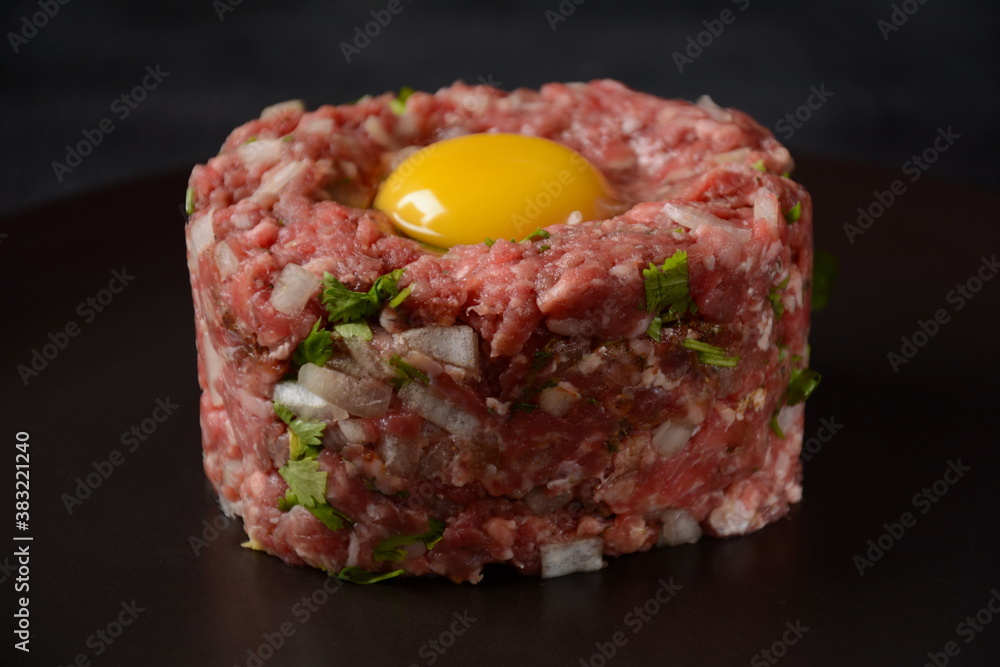 Beef tartare with raw egg, and onions, fresh herbs. French cuisine Beef tartare with raw egg, and onions, fresh herbs. French cuisine