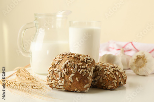 Fresh baked garlic buns and milk on white table