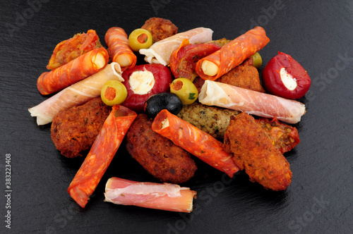 Group of savoury appetizer snacks including stuffed olives, lamb and chicken koftas and rollitos on a slate stone background photo