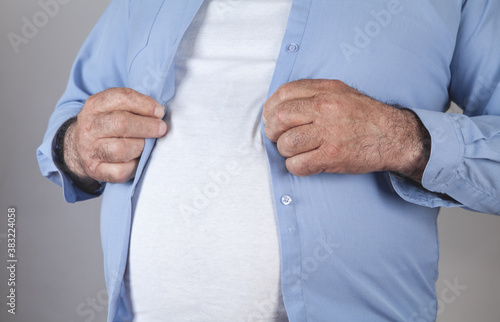  Fat man fastening buttons on shirt.