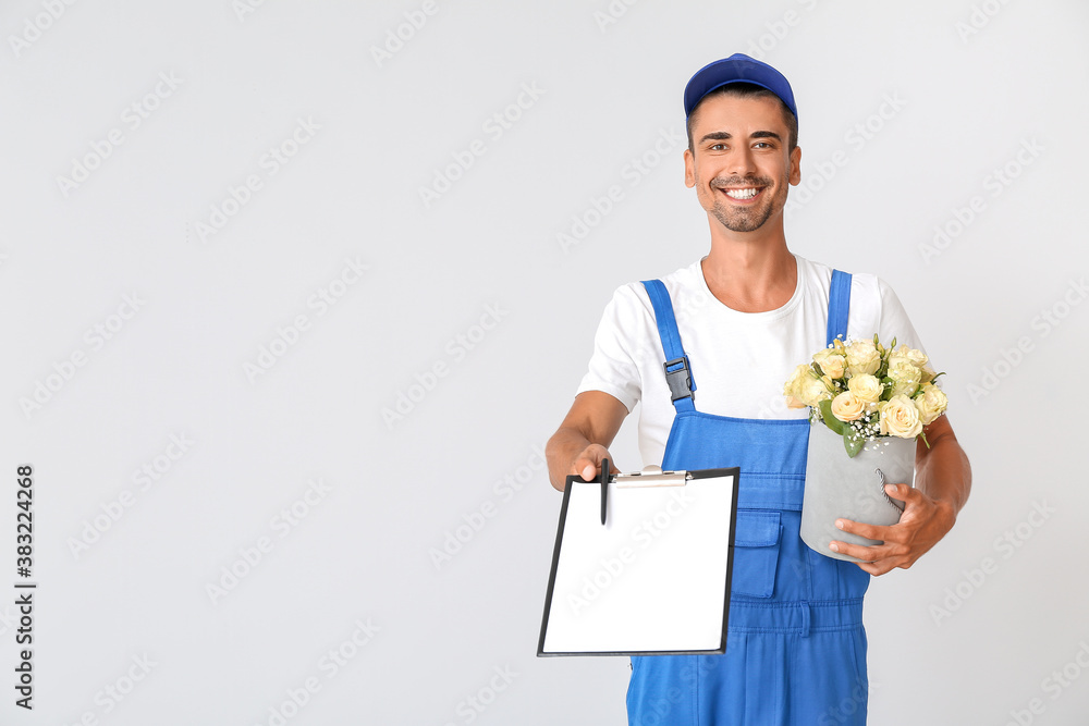 Delivery man with bouquet of flowers and clipboard on light background Delivery man with bouquet of flowers and clipboard on light background