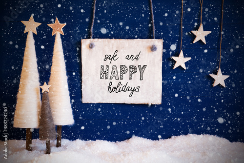 Wooden Sign With Engllish Text Safe And Happy Christmas. White Christmas Tree With Stars. Snow And Blue Background And Snowflakes photo