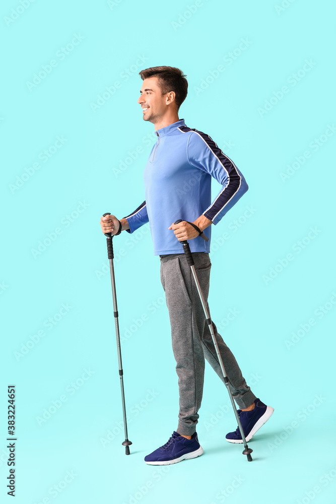 Young man with walking poles on color background Young man with walking poles on color background