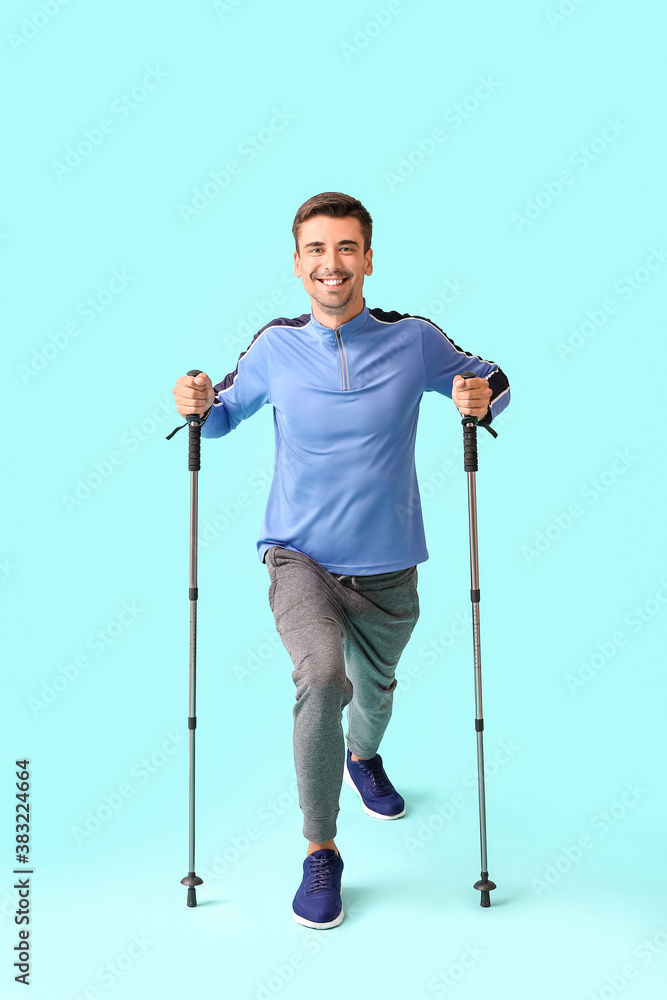Young man with walking poles on color background Young man with walking poles on color background