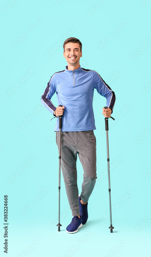 Young man with walking poles on color background Young man with walking poles on color background
