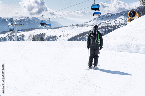 A man rides down the ski slope against the backdrop of snow-capped mountains and blue chair lifts .. The concept of sports, landscape, people. photo