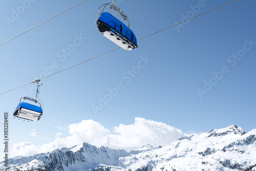 View of the snow-capped mountains and the cable car with blue chair cabins. Concept for sports, landscape, technology.