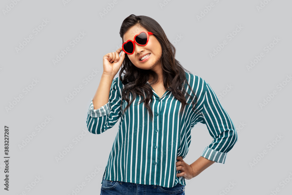 love, summer and valentines day concept - happy asian young woman in heart shaped sunglasses over grey background love, summer and valentines day concept - happy asian young woman in heart shaped sunglasses over grey background