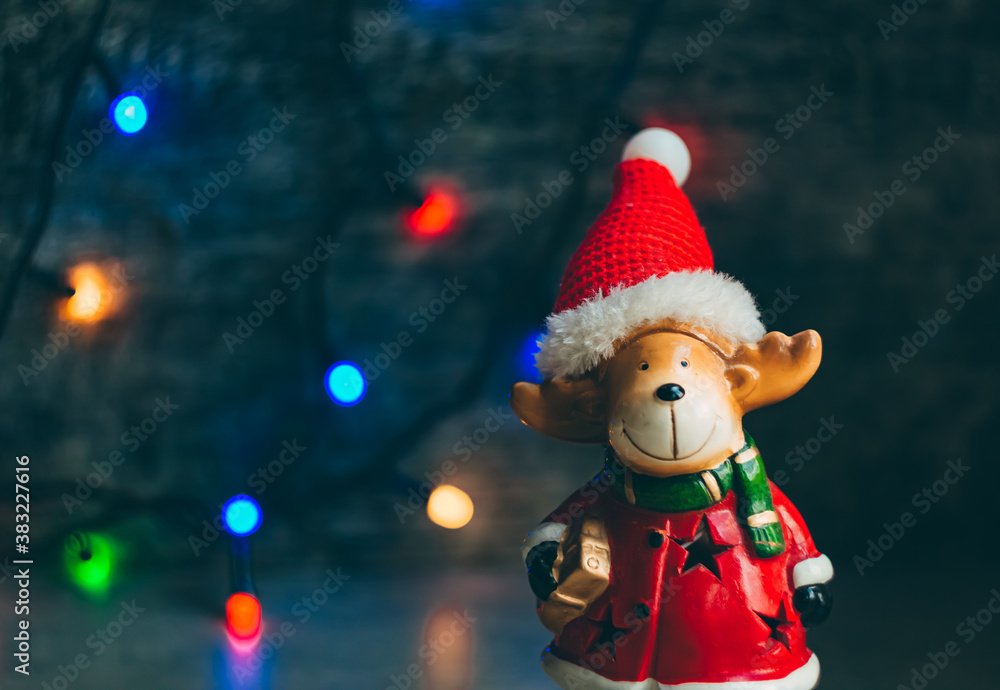 deer dressed as santa claus on the background of a dark wall with a christmas garland deer dressed as santa claus on the background of a dark wall with a christmas garland