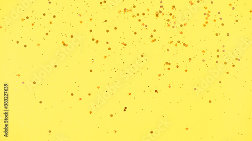 Gold glitter on yellow background. Holiday abstract