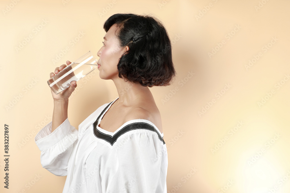 Portrait woman drinking water from the glass in pastels orange background. Healthy and lifestyle concept. Portrait woman drinking water from the glass in pastels orange background. Healthy and lifestyle concept.