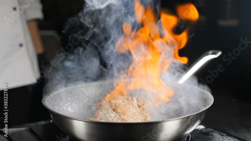 Cooking and serving food in restaurant. Chef making steak fillet mignon in flambe style on grill pan. Cooking slow motion. Cooking Beef meat Stroganoff with Open Flames. Full hd