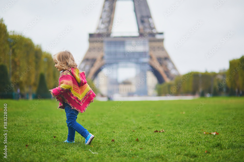 Adorable toddler girl near the Eiffel tower on a fall day in Paris, France