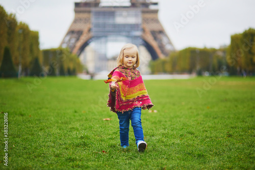 Adorable toddler girl near the Eiffel tower on a fall day in Paris, France