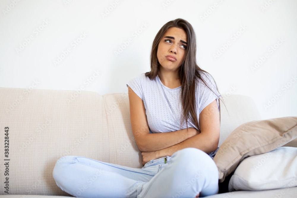 Woman in painful expression holding hands against belly suffering menstrual period pain,sitting sad on home bed, having tummy cramp in female health concept Woman in painful expression holding hands against belly suffering menstrual period pain,sitting sad on home bed, having tummy cramp in female health concept