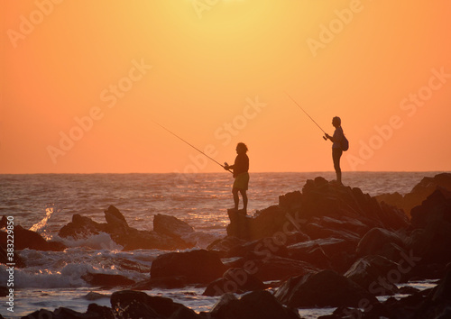 Two people fishing at sunset in Arambol beach, Goa.