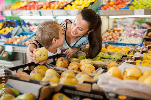 Cheerful positive mother with little boy buying pears and apples at store