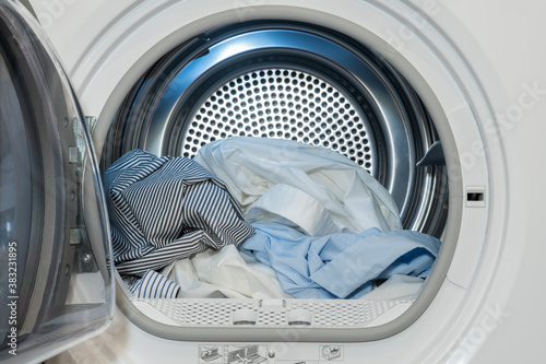 Close up view on clothes dryer machine with washed and dried shirts. photo