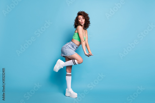 Profile photo of cute pretty sportive lady model look camera raised bent leg platform shoes sportswear shop advert concept wear green top jeans skirt isolated pastel blue color background