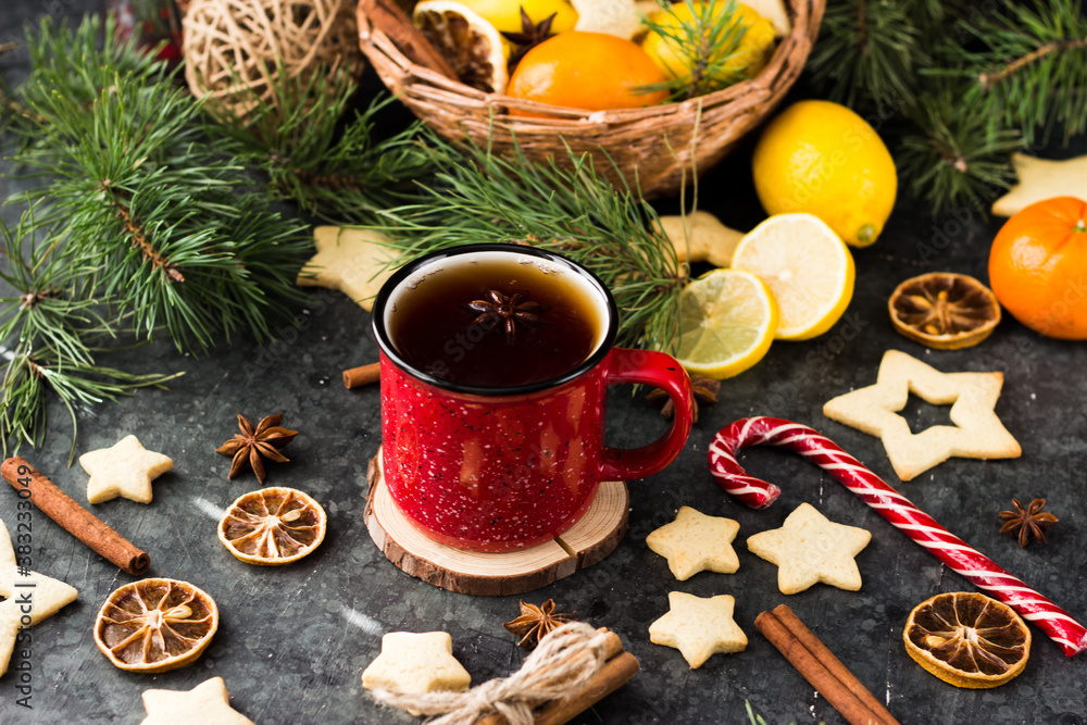 hot tea in a red mug in a new year's atmosphere. Christmas morning. A mug with a drink next to Christmas tree branches, oranges, spices and cookies