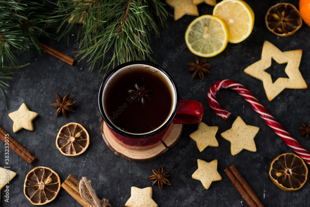 hot tea in a red mug in a new year's atmosphere. Christmas morning. A mug with a drink next to Christmas tree branches, oranges, spices and cookies