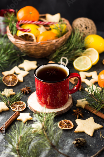 hot tea in a red mug in a new year's atmosphere. Christmas morning. A mug with a drink next to Christmas tree branches, oranges, spices and cookies