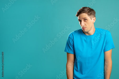 Doubtful male portrait. Regret mistake. Disengage emotion. Unsure look. Advertising background. Puzzled man looking at camera isolated on blue copy space.