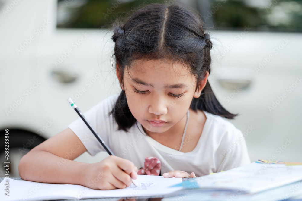 Portrait of a Little Asian girl is writing, for learning from home social distancing and quarantine concept, select focus shallow depth of field Portrait of a Little Asian girl is writing, for learning from home social distancing and quarantine concept, select focus shallow depth of field