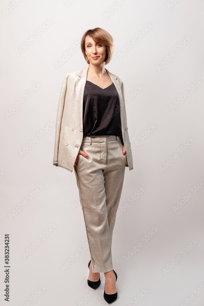 Successful female leader. Empowerment independence. Business fashion. Confident smart mature woman in stylish beige suit standing looking at camera smiling isolated on light neutral background. Successful female leader. Empowerment independence. Business fashion. Confident smart mature woman in stylish beige suit standing looking at camera smiling isolated on light neutral background.