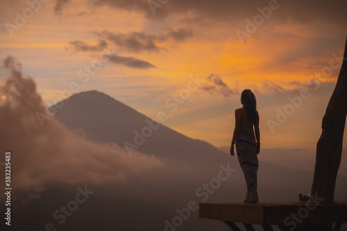 Silhouette of a girl in a long dress stands with Bali landmark volcano Agung view. Travel blogger, Indonesia best sunset point destination. Woman retreat. High quality photo