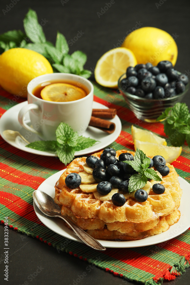 Belgian waffles with blueberry and a cup of tea with lemon Belgian waffles with blueberry and a cup of tea with lemon