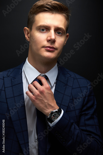 confident business man in formal tux or suit expresses his greatness and influence through his eyes, he looks at camera isolated over black background