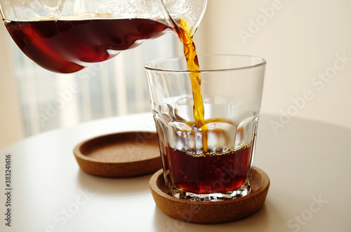 Black filter coffee pours from a jug into a glass close up. Specialty third wave concept