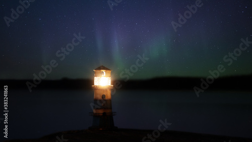 Beautiful night seascape with lighthouse and northen lights. Amazing green Aurora Borealis over the lighthouse. Night photography.