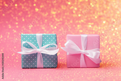 Fototapeta Naklejka Na Ścianę i Meble -  Pink and blue gift boxes with white bows over holiday defocused lights