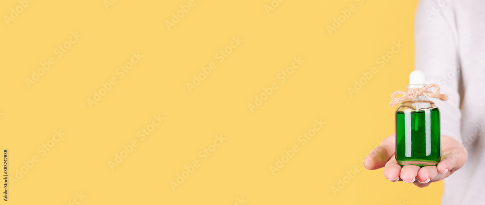 Hand with aroma oil bottle. Isolated on yellow background, copy space template, banner. Hand with aroma oil bottle. Isolated on yellow background, copy space template, banner.