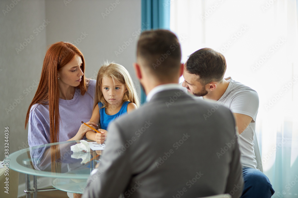 Fototapeta premium rear view on psychologist listening to family problems, they sit at table talking. children trauma due to divorce of parents